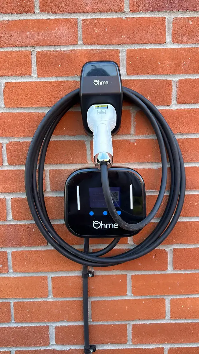 A home EV charger fitted to a red brick wall in Lincoln