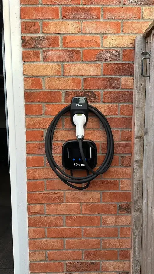 A tethered home EV charger on a brick wall