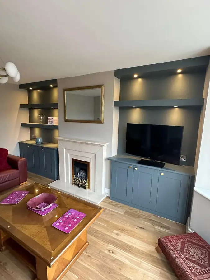 A grey media wall with a fireplace and TV